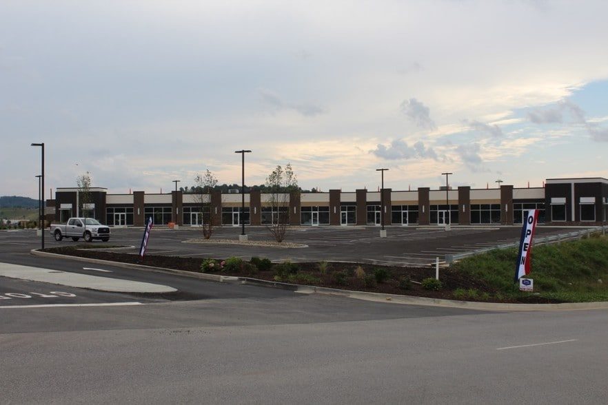 Newly completed retail storefronts at Morgantown Shoppes, with fresh parking and an open-for-business banner