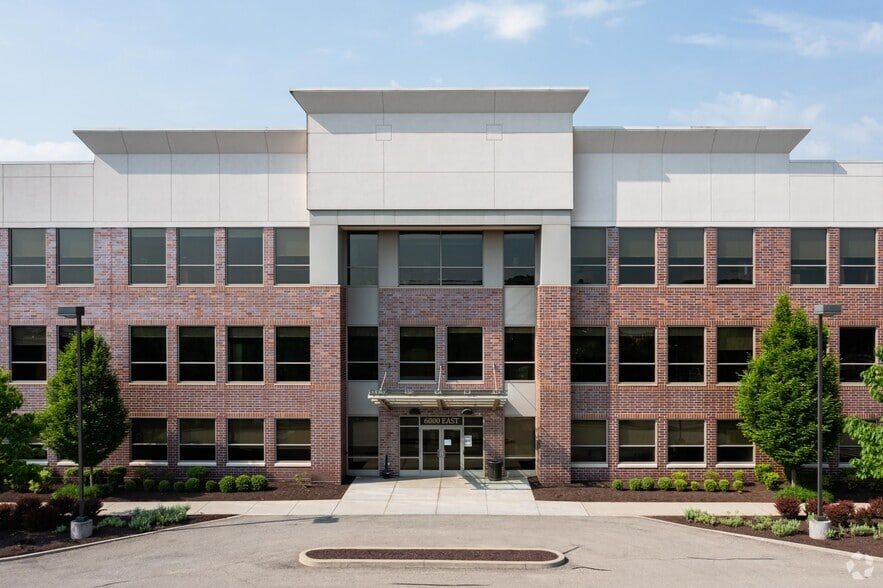 Main entrance of the 6000 East building at Embassy Park, framed by brick piers and landscaping