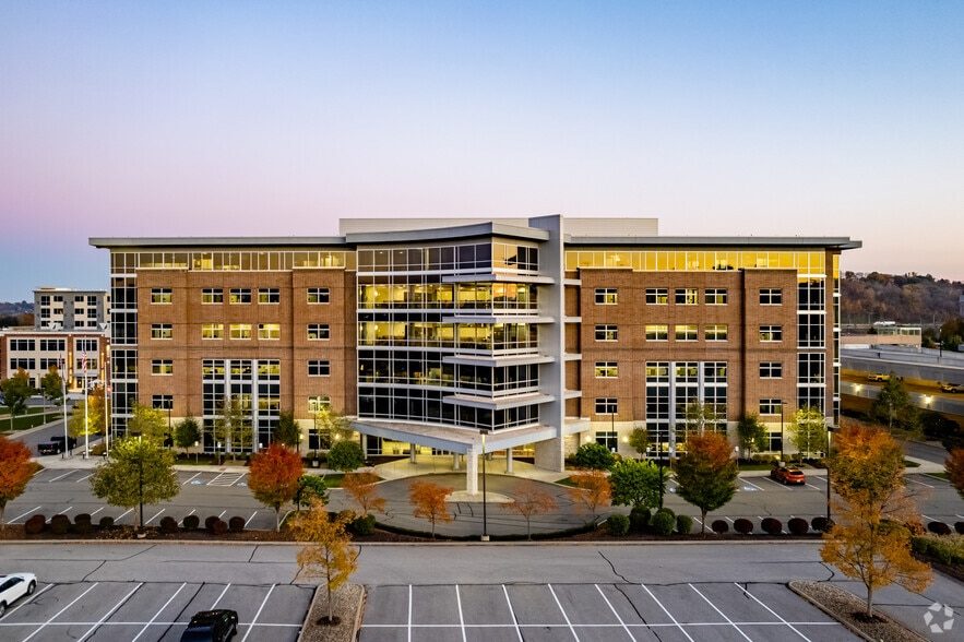 Town Square Office Building at dusk, its lit atrium and brick elevation seen from the parking lot