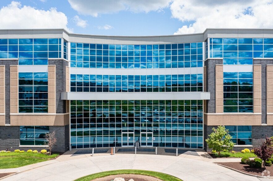 The curved glass entrance facade of 4000 Town Center Blvd seen from the front drive